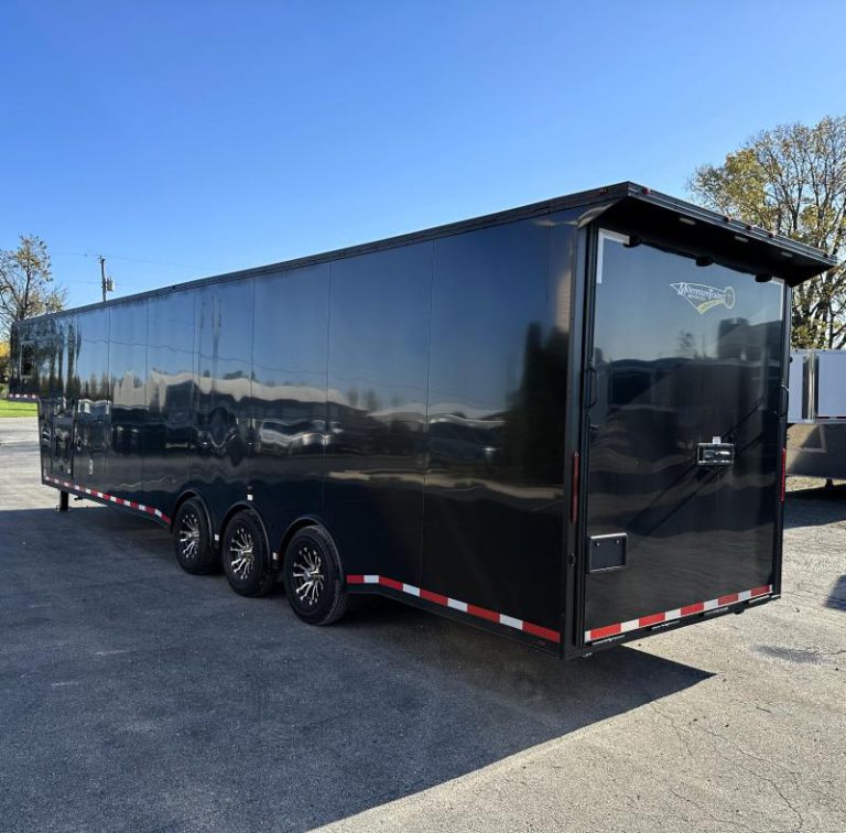 Enclosed Gooseneck Trailer 2023 40' Rear Exterior Roadside View. Black .040 Screwless Exterior, Rear Ramp Door, Rear Wing, Aluminum Wheels, LED Lights.