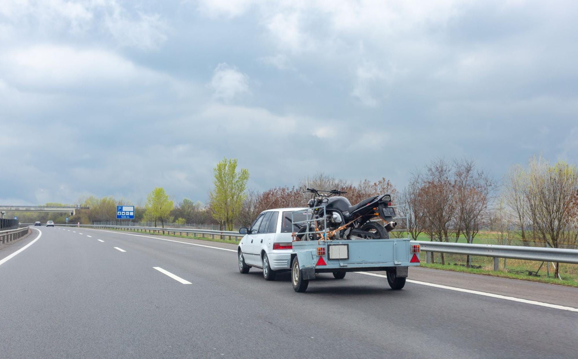 white car with a motorcycle on a trailer