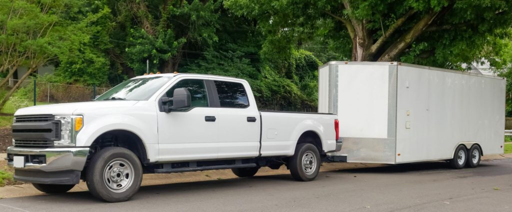 [White pickup truck and large utility trailer