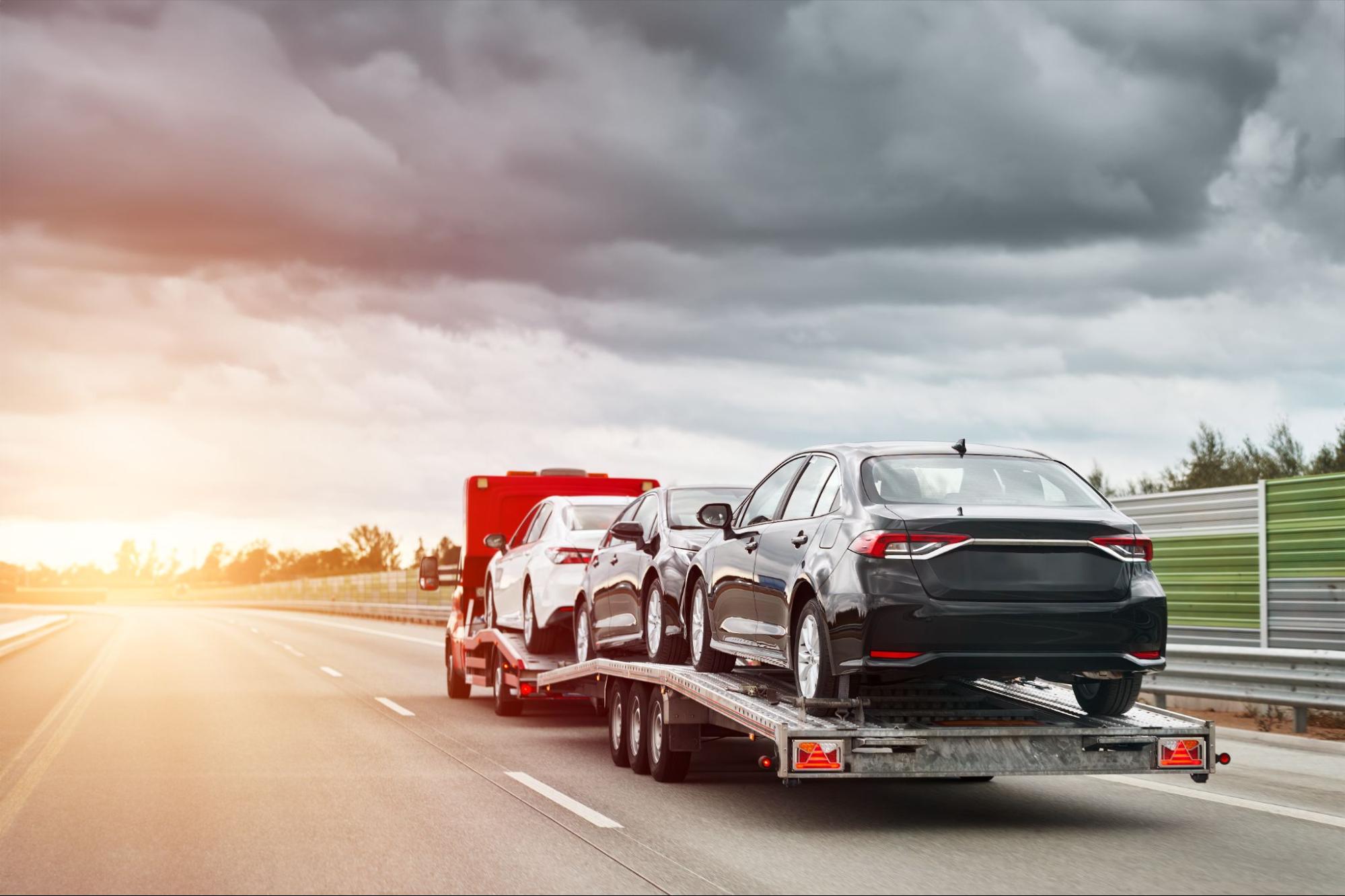 a truck towing a car trailer loaded with three cars